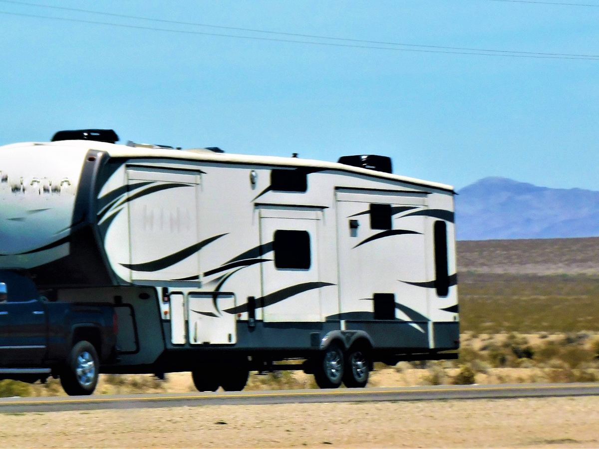 Travel trailer parked on a gravel lot under a blue sky